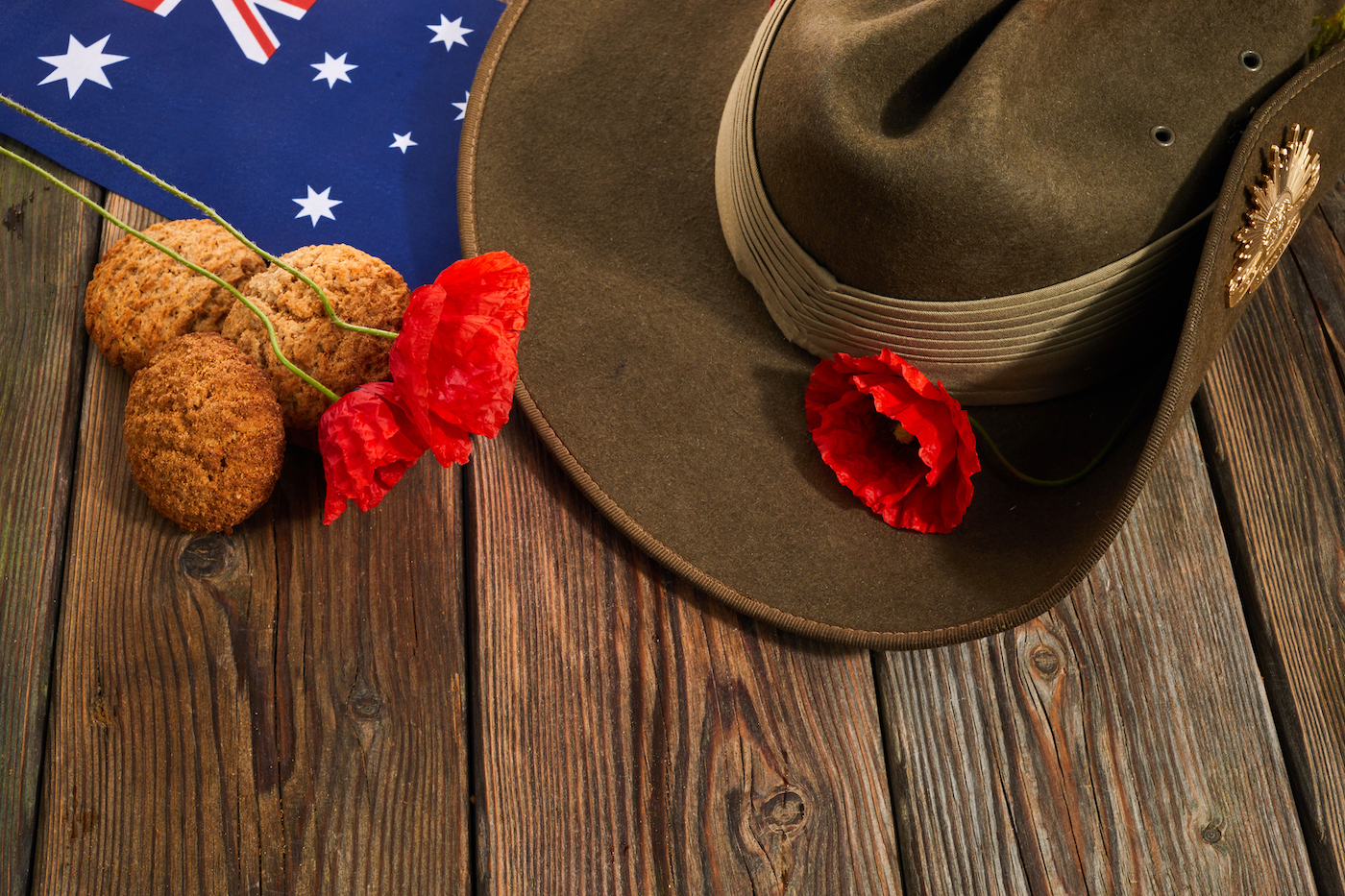 Australian Anzac Day. Australian army slouch hat red poppy and traditional Anzac biscuits on wooden background